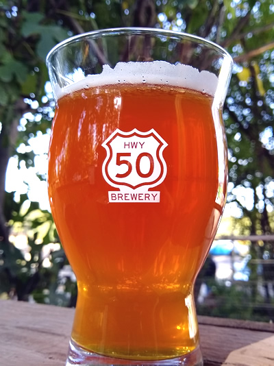 Light amber colored beer in glass with Hwy 50 Brewery logo