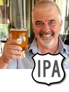 Smiling brewer, Gary Ritz, holding a pint glass of Backroad IPA.