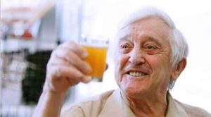 Man holding small glass of beer.