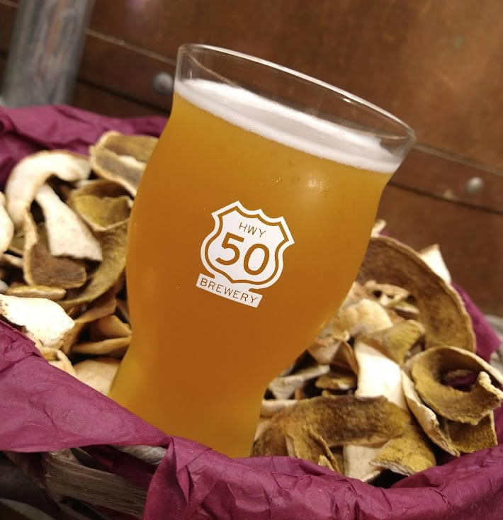 Glass of beer sitting in basket of dried orange peels.