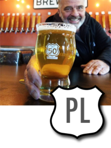 Brewer Gary Ritz, holding pint of pale lager on bar top.
